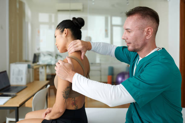 Sports massage specialist massaging neck and shoulder of female patient Sports massage specialist massaging neck and shoulder of female patient
